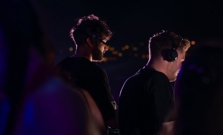 Two DJs performing together at a booth